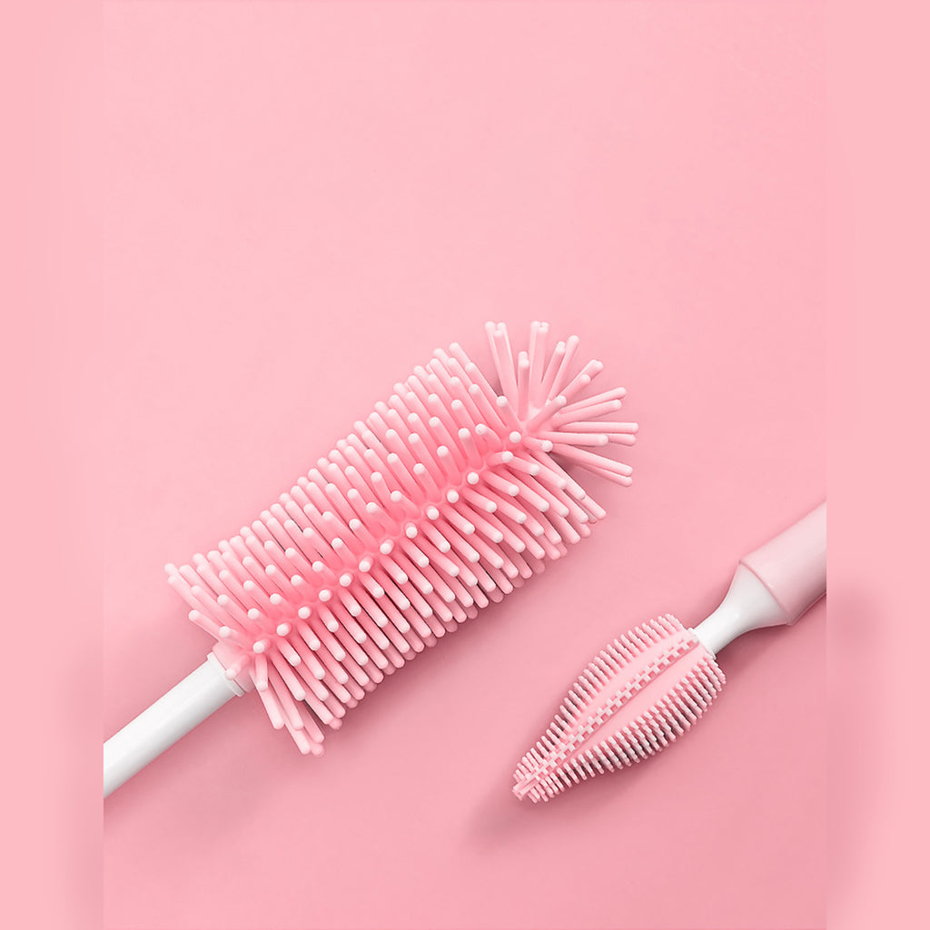 Two bottle brushes with pink bristle heads on a pink background