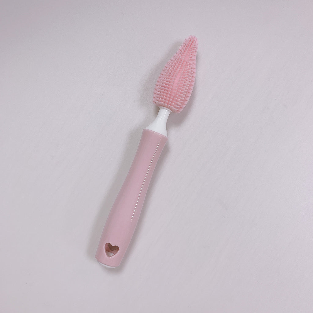 Pink brush with a heart-shaped hole on a light gray background