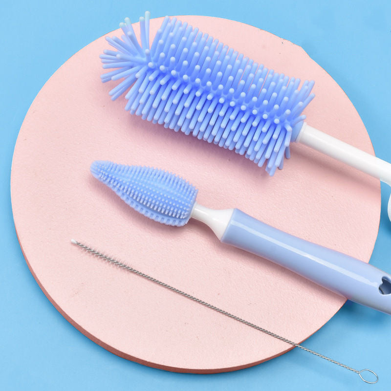 Two blue silicone bottle brushes on a pink circular pad with a blue background