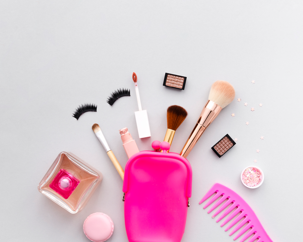 Makeup tools including brushes, a pink case, and cosmetic items on a light gray background